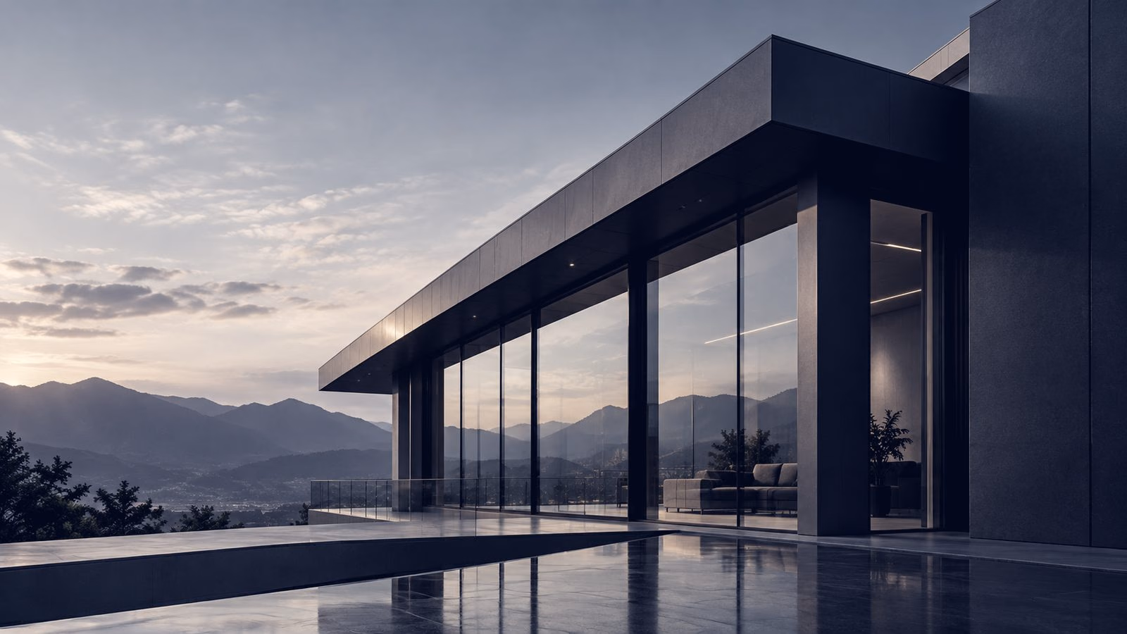 A modern glass house at dusk with the interior lit