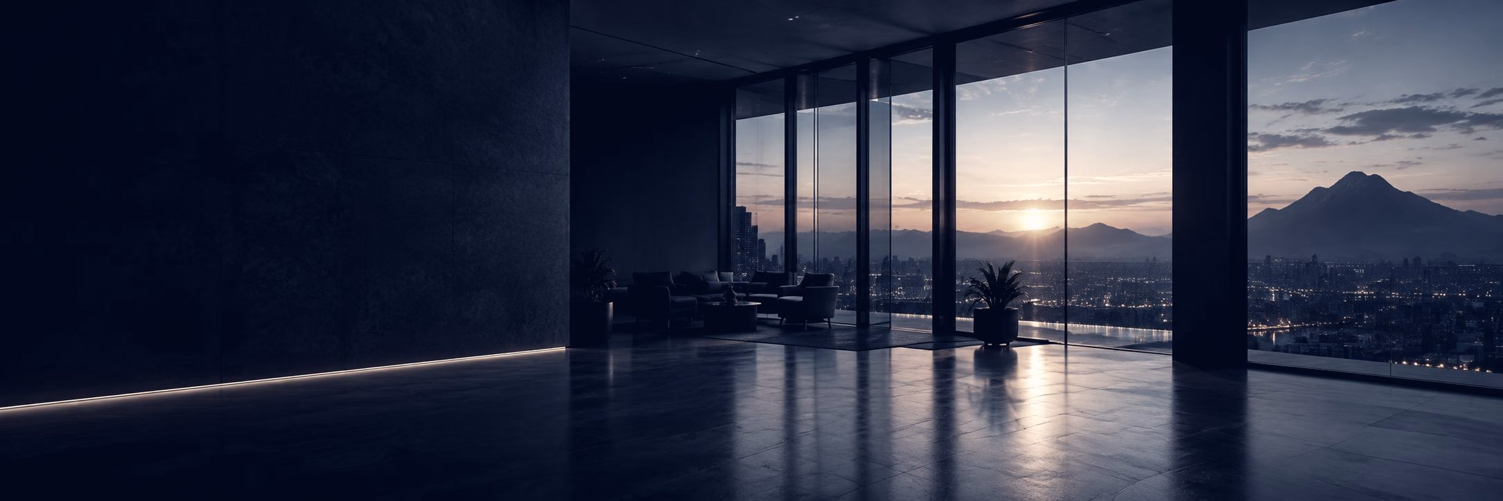 An office at dusk with floor-to-ceiling windows looking out to a mountain skyline